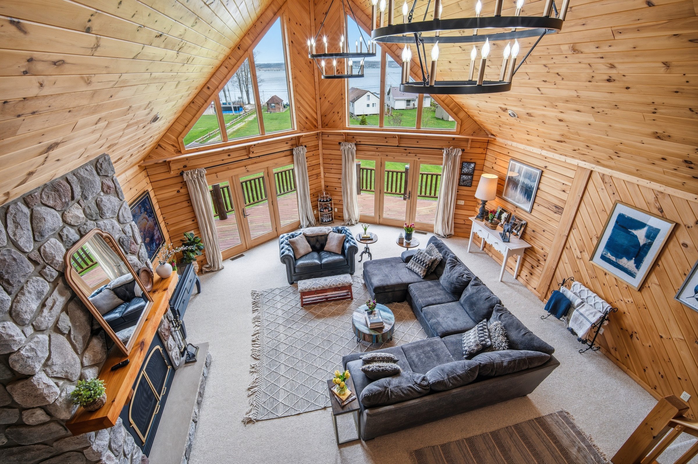 Great room from the loft — vaulted ceiling, stone fireplace, wall of lake windows